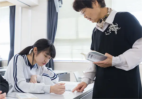 学生が教室で教員から個別にアドバイスを受けている様子。質問しやすく、丁寧なサポートが行われている。