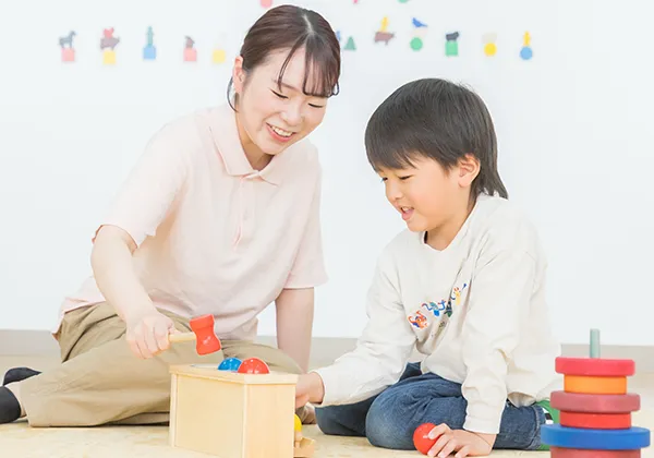 学生が室内で園児と楽しく遊んでいる様子。