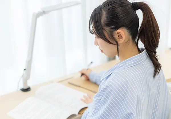 静かな教室でノートに向かう学生。資格取得に向けて前向きに学ぶ姿をイメージさせる写真。